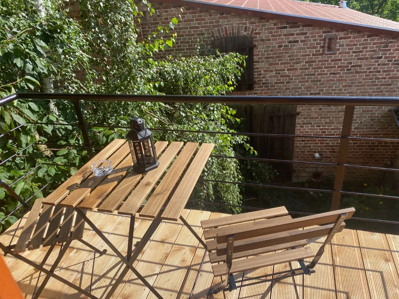 Ferienwohnung III: Balkon mit Bistrotisch und Stühlen, gegenüber die alte Scheune