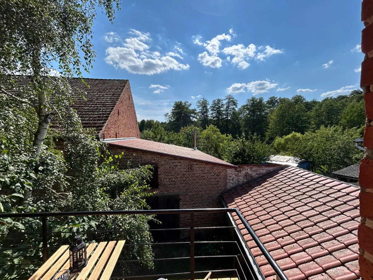 Blick vom Balkon der Ferienwohnung III über die Ziegeldächer des Hofes und die Baumkronen